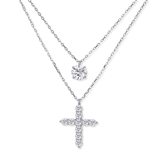 Two delicate sterling silver necklaces with moissanite stones - one solitaire pendant and one cross pendant on white background.