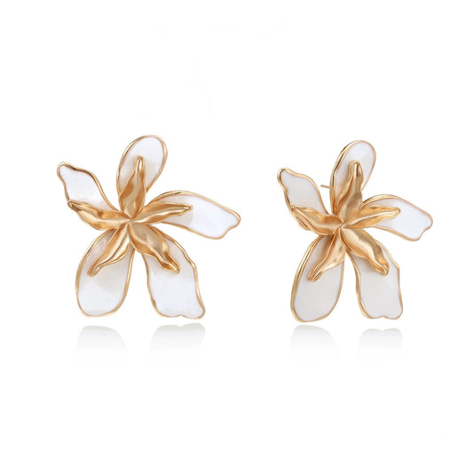 White enamel tropical flower earrings with sculptural gold-plated center and organic petal design on cream background