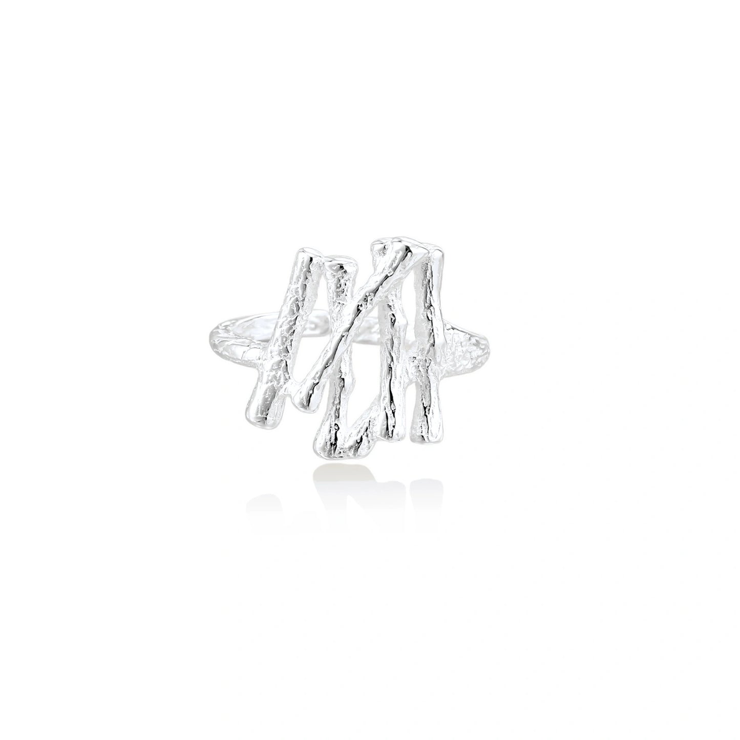 Sculptural sterling silver ring with organic branch design and textured surfaces on cream background